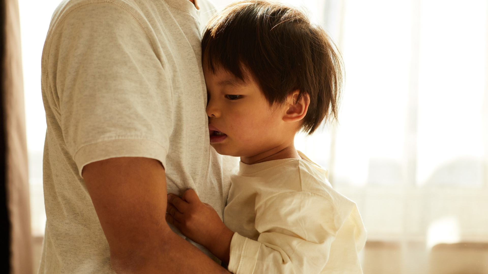 Child hugging an adult closely, looking anxious